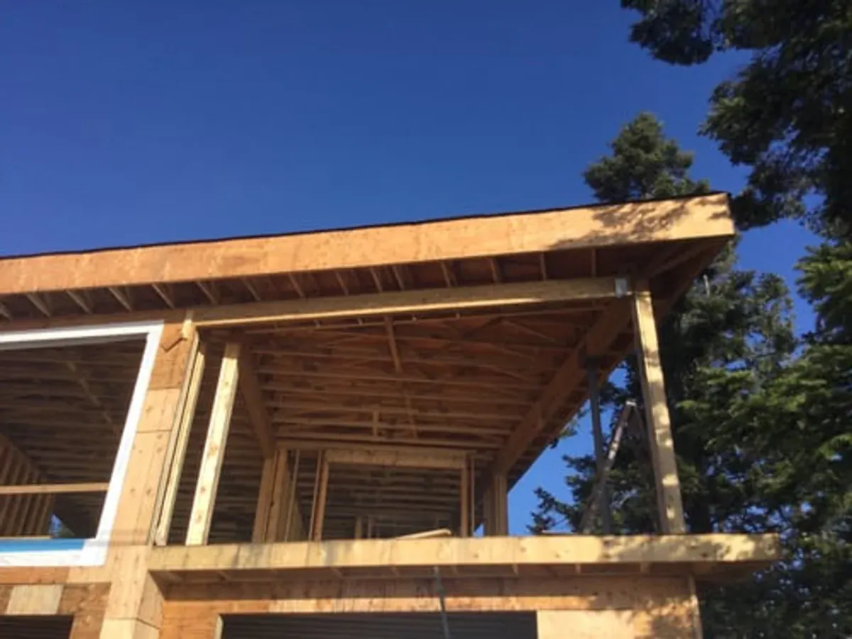 Framed second-storey home addition under a clear blue sky surrounded by pine trees near Big Bear Lake